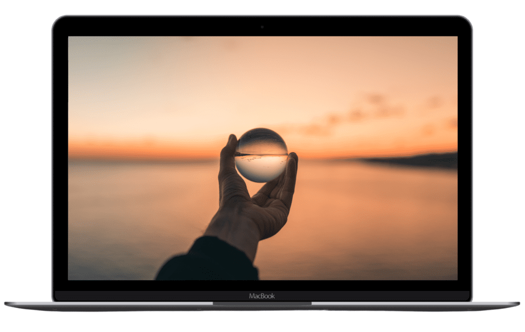 A hand holding a glass ball with a clearer image of the sea and land in the background