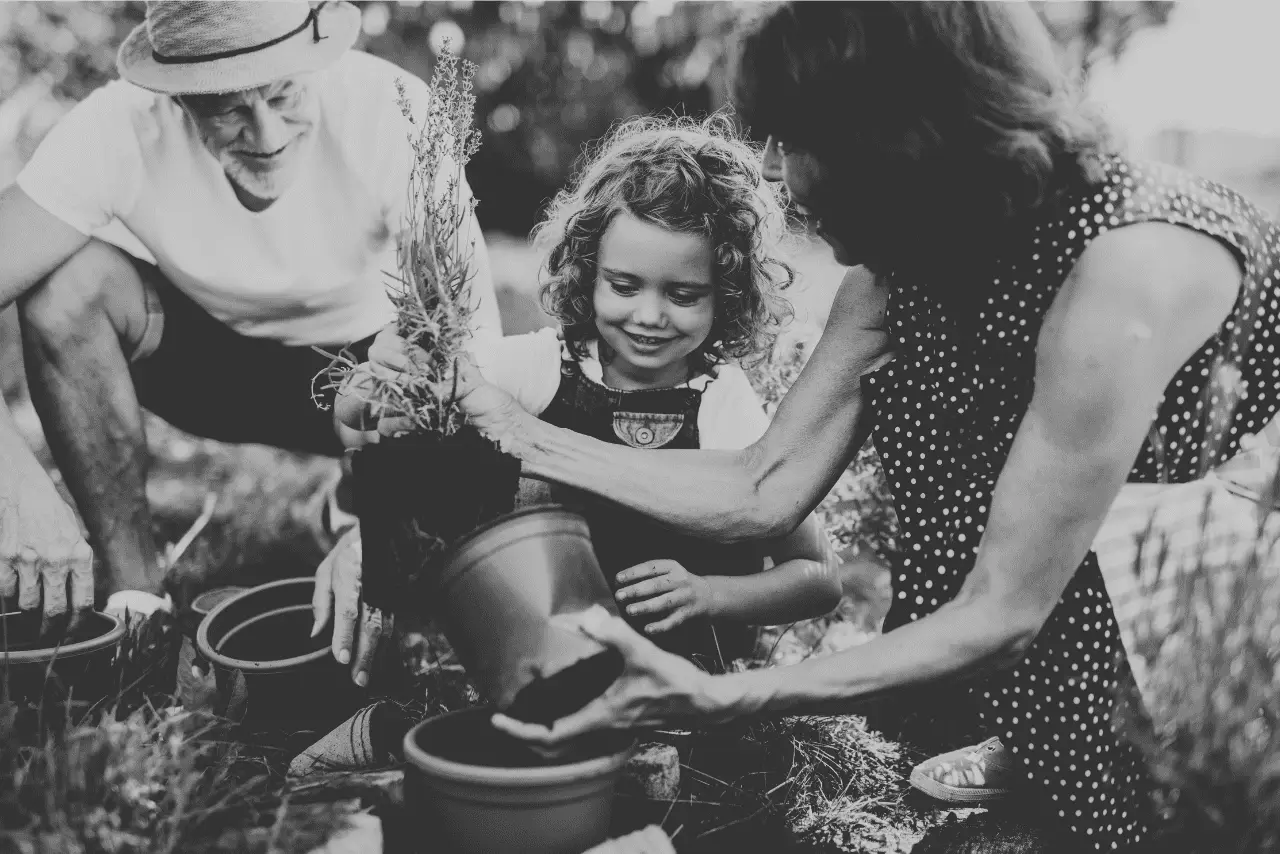 Grandparents enjoying gardening with their granddaughter, as they plan herbs