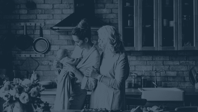 Retired grandmother, her daughter, and a grandchild in the kitchen smiling