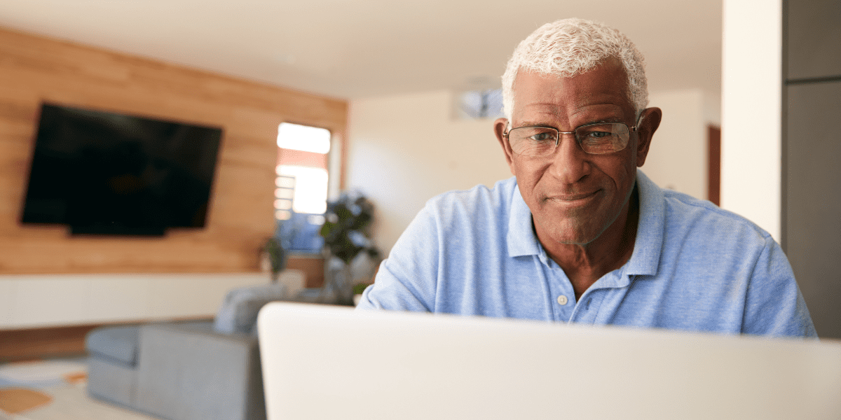 Retired Man Looking at His Laptop In His Living Room